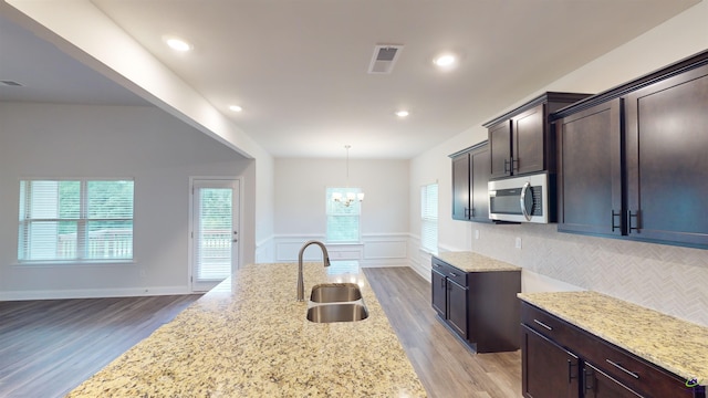 444 Southern Oaks Dr, Macon, GA 31216 - kitchen featuring a sink, stainless steel microwave, light wood-type flooring, light stone counters, and dark brown cabinets
