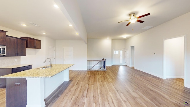 444 Southern Oaks Dr, Macon, GA 31216 - kitchen featuring a sink, stainless steel microwave, a ceiling fan, light wood-type flooring, and an island with sink