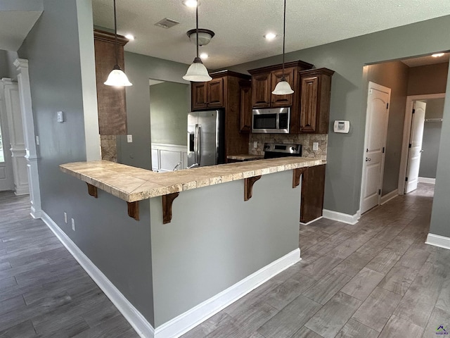 228 Piedmont Ln, Bonaire, GA 31005 - kitchen featuring stainless steel appliances, light countertops, a kitchen bar, dark wood-style floors, and a textured ceiling