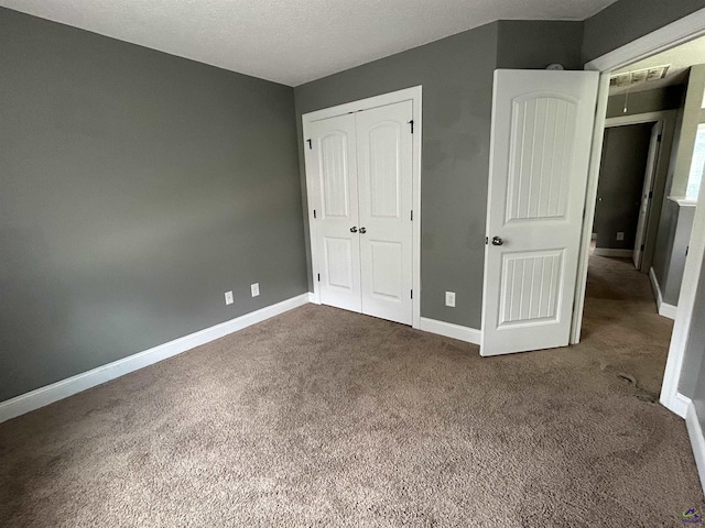 228 Piedmont Ln, Bonaire, GA 31005 - unfurnished bedroom with dark carpet, a closet, and a textured ceiling