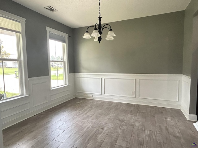 228 Piedmont Ln, Bonaire, GA 31005 - unfurnished dining area with a chandelier, wainscoting, wood finished floors, healthy amount of natural light, and a textured ceiling