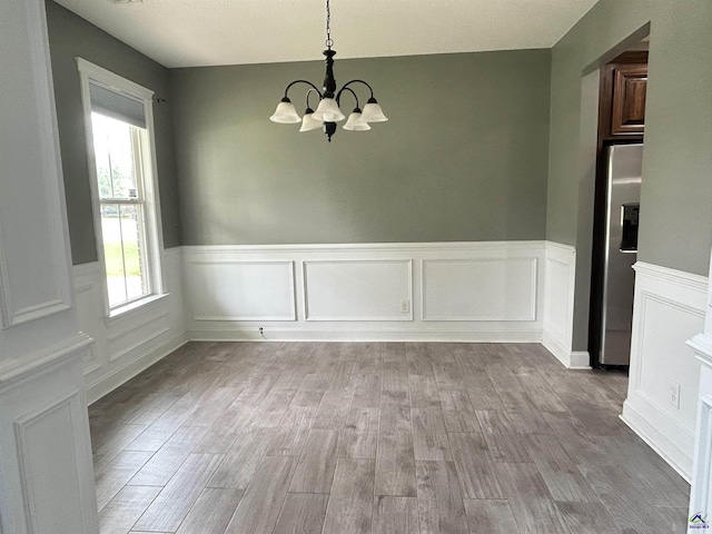 228 Piedmont Ln, Bonaire, GA 31005 - unfurnished dining area with a chandelier, wainscoting, wood finished floors, and a decorative wall