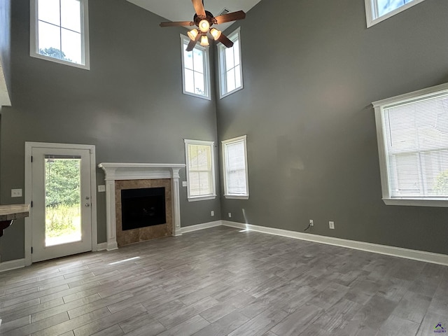 228 Piedmont Ln, Bonaire, GA 31005 - unfurnished living room featuring a towering ceiling, ceiling fan, wood finished floors, a tiled fireplace, and plenty of natural light