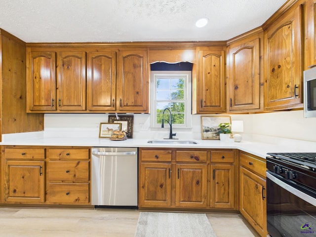 3610 Bonanza Dr, Macon, GA 31216 - kitchen with dishwasher, range with gas stovetop, brown cabinetry, light countertops, and a textured ceiling