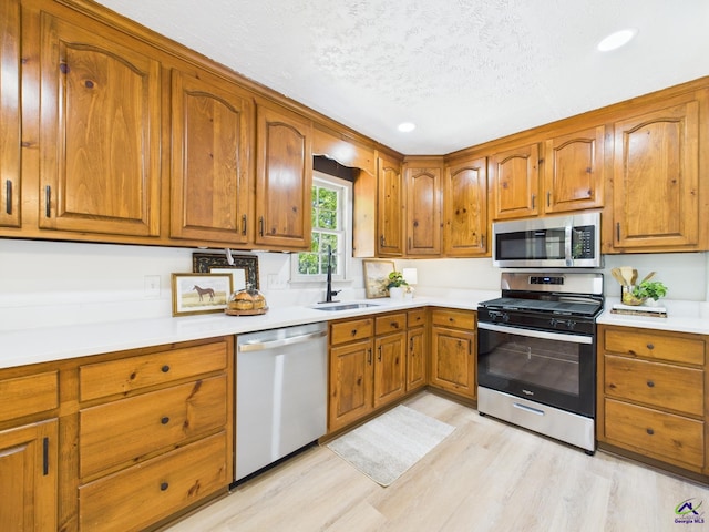 3610 Bonanza Dr, Macon, GA 31216 - kitchen with appliances with stainless steel finishes, brown cabinets, light wood finished floors, a textured ceiling, and light countertops