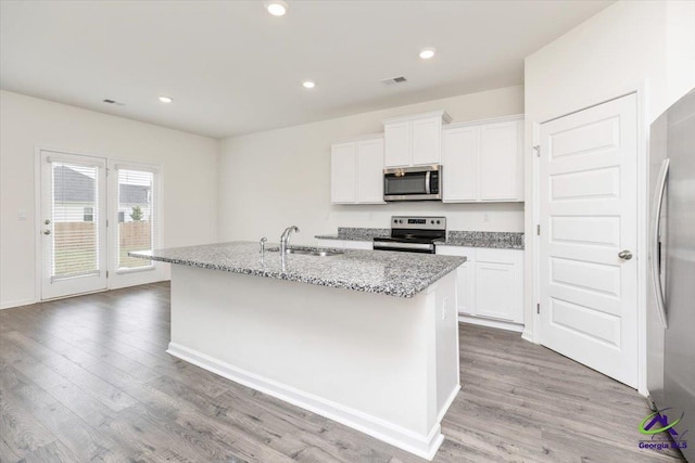 111 Farmers Way, Perry, GA 31069 - kitchen featuring stainless steel appliances, a kitchen island with sink, light stone countertops, light wood-type flooring, and white cabinets