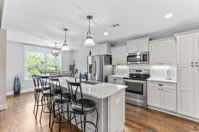 304 Kendall Ct, Perry, GA 31069 - kitchen with appliances with stainless steel finishes, an island with sink, decorative backsplash, dark wood-style flooring, and a breakfast bar