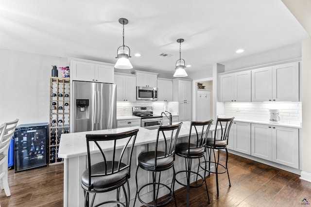 304 Kendall Ct, Perry, GA 31069 - kitchen featuring appliances with stainless steel finishes, dark wood-style floors, recessed lighting, tasteful backsplash, and a kitchen breakfast bar