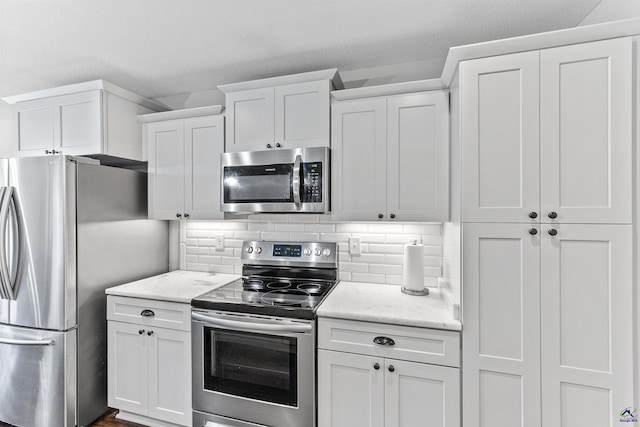 304 Kendall Ct, Perry, GA 31069 - kitchen with appliances with stainless steel finishes, white cabinets, decorative backsplash, and light stone counters
