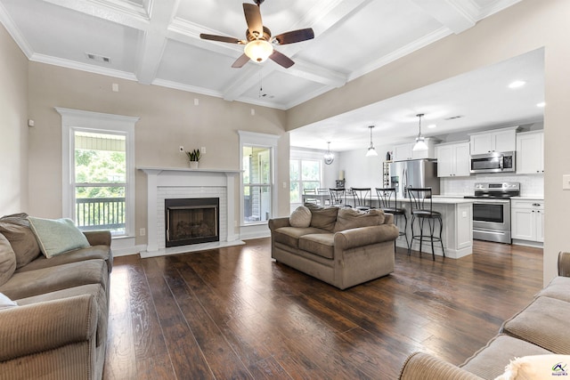 304 Kendall Ct, Perry, GA 31069 - living room featuring a ceiling fan, beamed ceiling, dark wood-style flooring, a brick fireplace, and crown molding