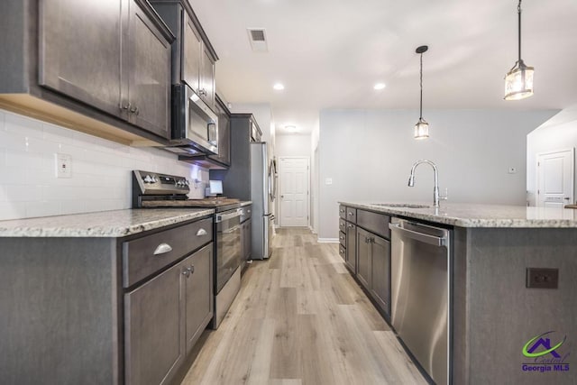 501 Adirondac Way, Bonaire, GA 31005 - kitchen with stainless steel appliances, dark brown cabinets, light wood-style flooring, a center island with sink, and decorative backsplash