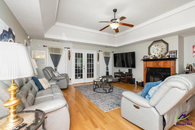 222 Duke Ln, Kathleen, GA 31047 - living area featuring a tray ceiling, ceiling fan, a fireplace, wood finished floors, and french doors