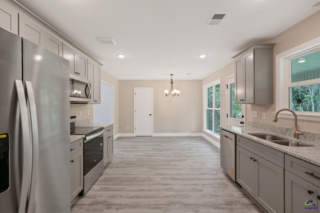 219 Christine Cir, Perry, GA 31069 - kitchen featuring appliances with stainless steel finishes, gray cabinets, a chandelier, light wood-style floors, and light stone countertops
