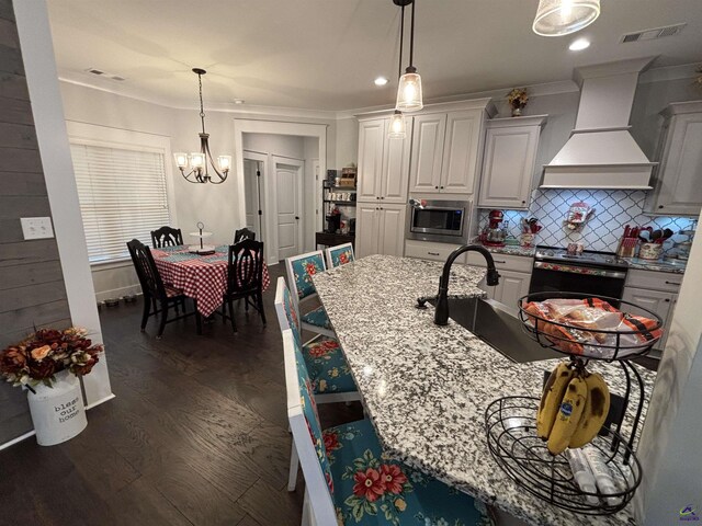 400 Rustic Live Oak Trl, Bonaire, GA 31005 - kitchen with premium range hood, stainless steel microwave, a chandelier, dark wood-style floors, and white cabinetry