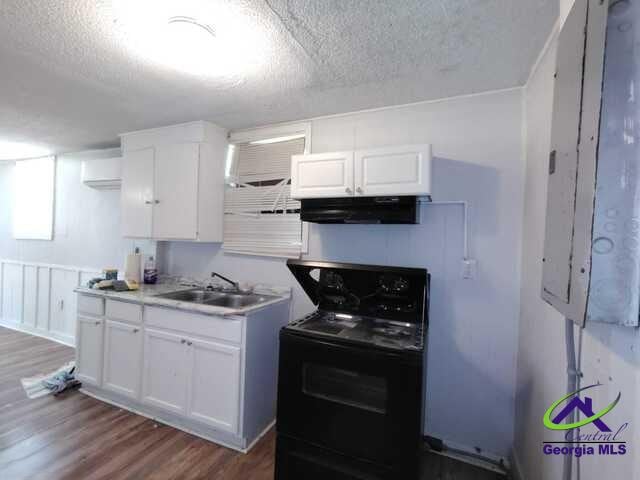 107 Roberts St, Warner Robins, GA 31093 - kitchen with black electric range, ventilation hood, a textured ceiling, wood finished floors, and white cabinetry