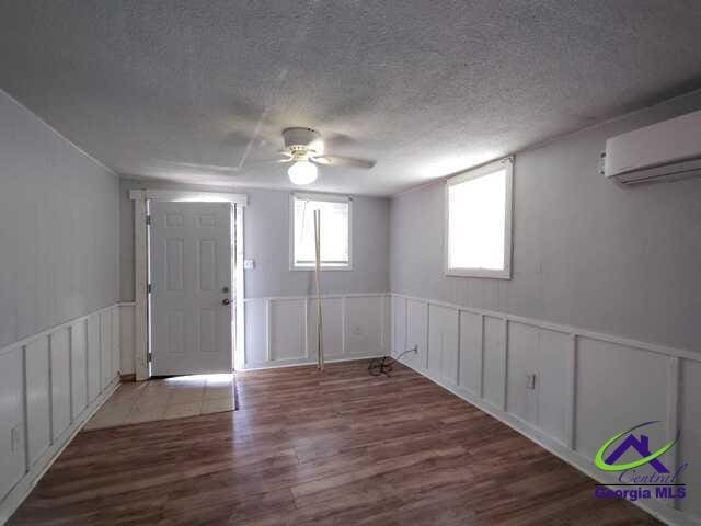 107 Roberts St, Warner Robins, GA 31093 - entryway with ceiling fan, a wall mounted air conditioner, wood finished floors, a decorative wall, and a textured ceiling