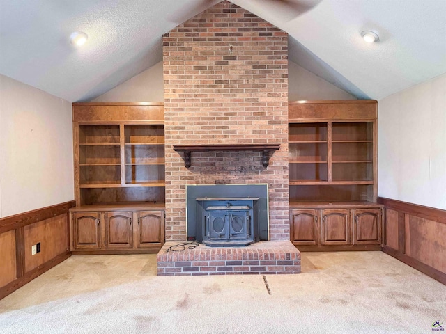7285 Nowell Rd S, Macon, GA 31216 - unfurnished living room with vaulted ceiling, a wood stove, carpet, wainscoting, and a textured ceiling
