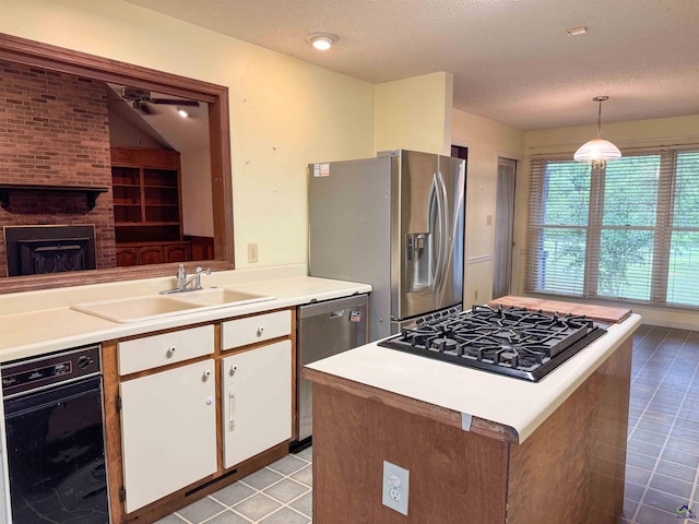 7285 Nowell Rd S, Macon, GA 31216 - kitchen with stainless steel appliances, white cabinets, light countertops, a textured ceiling, and a kitchen island