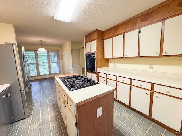 7285 Nowell Rd S, Macon, GA 31216 - kitchen with black appliances, a textured ceiling, light countertops, white cabinetry, and a kitchen island