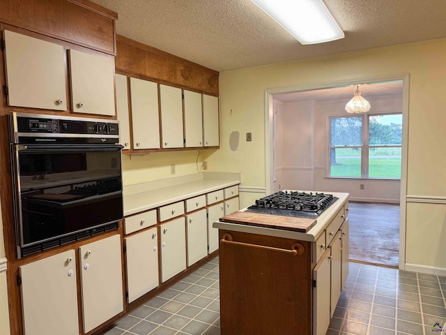 7285 Nowell Rd S, Macon, GA 31216 - kitchen featuring gas cooktop, a textured ceiling, a center island, and white cabinetry