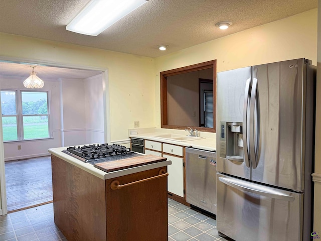 7285 Nowell Rd S, Macon, GA 31216 - kitchen with appliances with stainless steel finishes, light countertops, a textured ceiling, a center island, and a chandelier