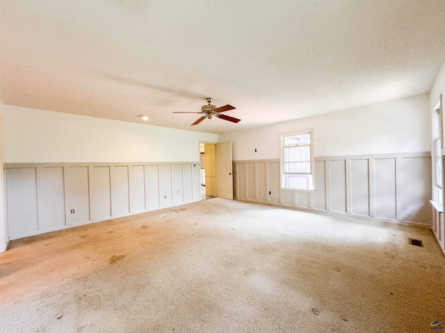 7285 Nowell Rd S, Macon, GA 31216 - carpeted spare room featuring a textured ceiling, wainscoting, a ceiling fan, and a decorative wall