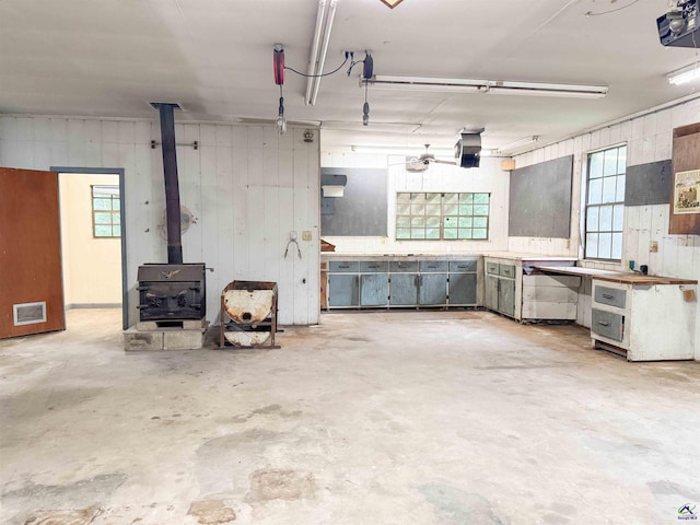 7285 Nowell Rd S, Macon, GA 31216 - garage featuring a garage door opener, wooden walls, and a wood stove