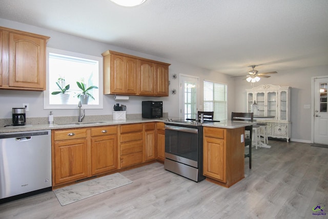 100 Scarlett Dr, Warner Robins, GA 31088 - kitchen featuring appliances with stainless steel finishes, light wood finished floors, a peninsula, a ceiling fan, and light stone countertops