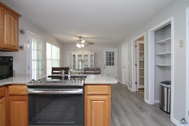 100 Scarlett Dr, Warner Robins, GA 31088 - kitchen with stainless steel electric range, ceiling fan, a peninsula, light wood-style floors, and light stone counters