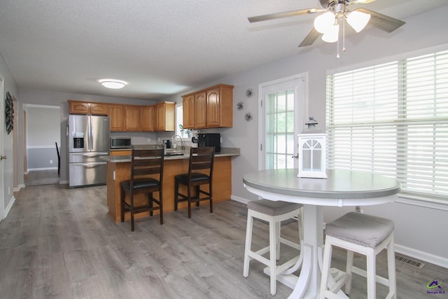 100 Scarlett Dr, Warner Robins, GA 31088 - kitchen featuring stainless steel appliances, a peninsula, a kitchen bar, light wood finished floors, and a textured ceiling