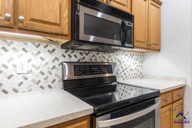 310 Woods Edge Way, Warner Robins, GA 31088 - kitchen with stainless steel electric range, decorative backsplash, and brown cabinets