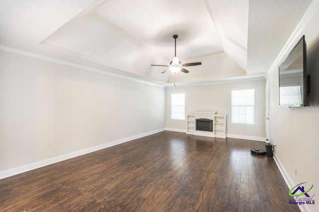 310 Woods Edge Way, Warner Robins, GA 31088 - unfurnished living room with a tray ceiling, a ceiling fan, dark wood-type flooring, a fireplace, and crown molding