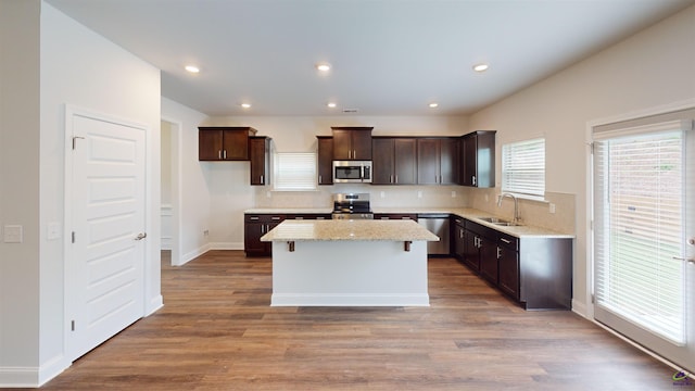 463 Southern Oaks Dr, Macon, GA 31216 - kitchen featuring stainless steel appliances, dark brown cabinetry, a kitchen island, wood finished floors, and light stone counters