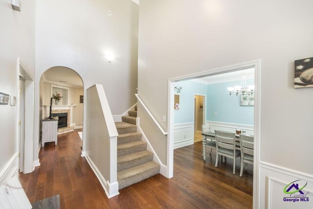 112 Verandah Ct, Bonaire, GA 31005 - staircase featuring a chandelier, a brick fireplace, wood finished floors, a high ceiling, and crown molding