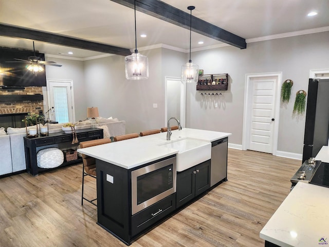 109 Raspberry Trl, Perry, GA 31069 - kitchen featuring appliances with stainless steel finishes, beam ceiling, a breakfast bar, dark cabinets, and light wood-style flooring
