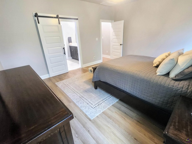 109 Raspberry Trl, Perry, GA 31069 - bedroom featuring a barn door, light wood-style flooring, and connected bathroom