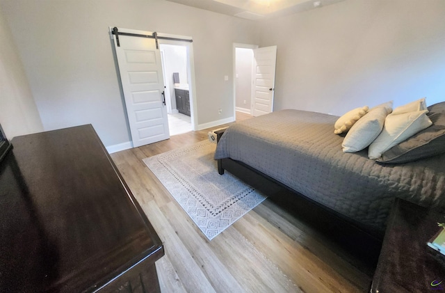 109 Raspberry Trl, Perry, GA 31069 - bedroom with a barn door, light wood finished floors, and ensuite bathroom