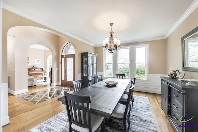 109 Black Oak Ct, Byron, GA 31008 - dining room with a chandelier, light wood-style flooring, arched walkways, crown molding, and wainscoting