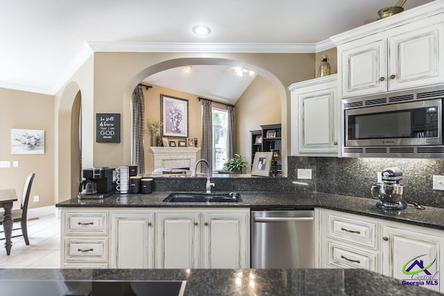 109 Black Oak Ct, Byron, GA 31008 - kitchen with stainless steel appliances, arched walkways, dark stone countertops, white cabinetry, and ornamental molding
