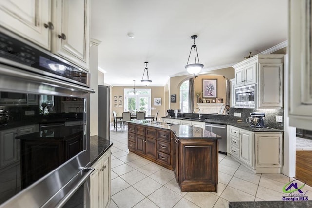 109 Black Oak Ct, Byron, GA 31008 - kitchen featuring appliances with stainless steel finishes, crown molding, arched walkways, cream cabinetry, and tasteful backsplash