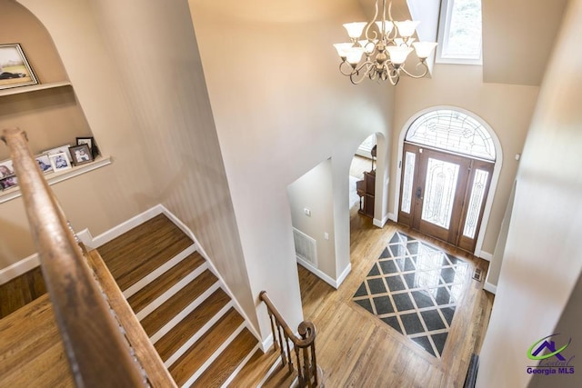 109 Black Oak Ct, Byron, GA 31008 - foyer featuring arched walkways, wood finished floors, a towering ceiling, a chandelier, and stairway