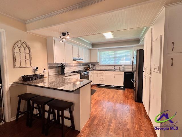 234 Briarcliff Rd, Warner Robins, GA 31088 - kitchen featuring a peninsula, appliances with stainless steel finishes, under cabinet range hood, wood finished floors, and white cabinetry