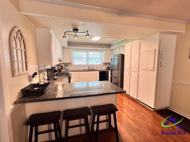 234 Briarcliff Rd, Warner Robins, GA 31088 - kitchen with black appliances, wood finished floors, a peninsula, ornamental molding, and tasteful backsplash