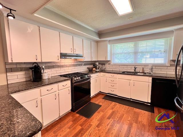 234 Briarcliff Rd, Warner Robins, GA 31088 - kitchen featuring black appliances, under cabinet range hood, white cabinetry, backsplash, and crown molding