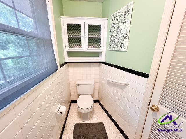 234 Briarcliff Rd, Warner Robins, GA 31088 - half bath featuring a wainscoted wall, tile walls, and tile patterned floors
