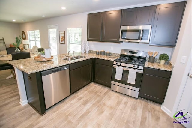 312 Cody Dr, Macon, GA 31216 - kitchen featuring stainless steel appliances, light wood finished floors, a peninsula, light stone countertops, and open floor plan