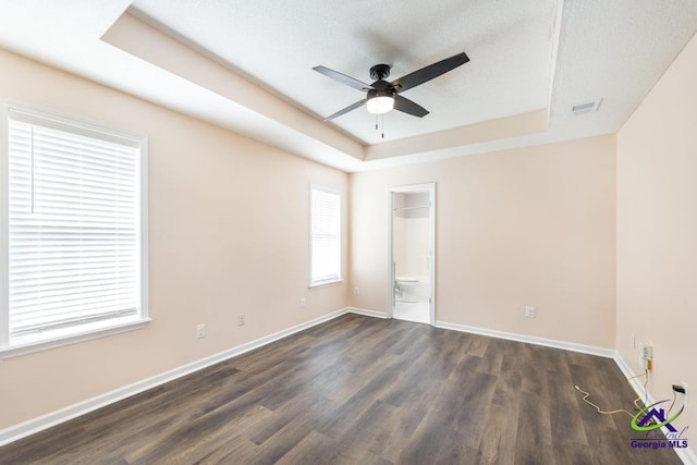 313 Strawbridge Ln, Bonaire, GA 31005 - unfurnished bedroom with a tray ceiling, dark wood-style flooring, and ensuite bathroom