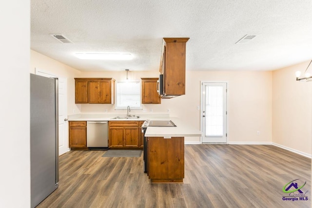 313 Strawbridge Ln, Bonaire, GA 31005 - kitchen featuring appliances with stainless steel finishes, brown cabinets, a peninsula, dark wood-style floors, and a textured ceiling