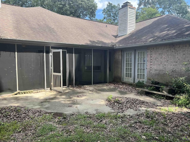 318 Pheasant Rdg, Warner Robins, GA 31088 - rear view of property featuring a sunroom, a chimney, brick siding, roof with shingles, and a patio