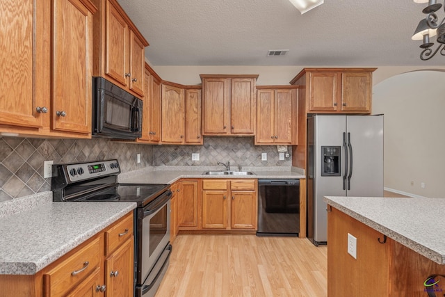 112 Finegand Pl, Warner Robins, GA 31088 - kitchen with black appliances, light wood-style floors, light countertops, arched walkways, and a textured ceiling